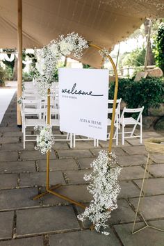 a sign that is sitting on some kind of metal stand with flowers in front of it