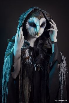 a woman with an owl mask on holding her hands to her face