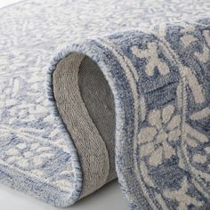 a blue and white rug laying on top of a white floor next to a wall