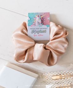 a pink hair scrunch on top of a white table next to pearl beads