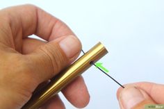 a person is holding a small metal object with a green arrow in it's hand