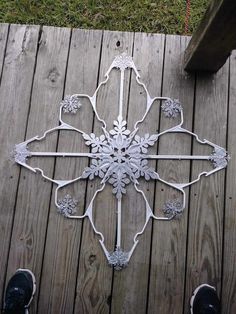 a white metal snowflake sitting on top of a wooden deck