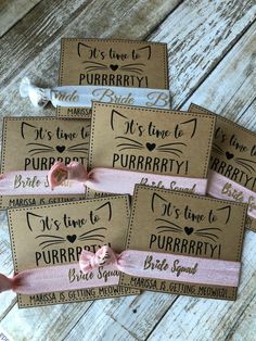 four brown tags with pink bows on them sitting on top of a wooden table next to each other