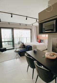 a living area with a bed, television and dining table in it's center