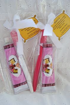 two pink toothbrushes in plastic bags on a white tablecloth with tags attached to them