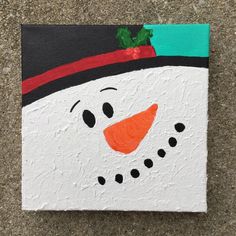 a painting of a snowman wearing a black hat and green scarf on a brick wall