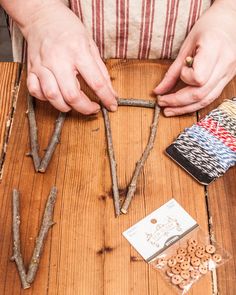 two hands are working on some kind of crafting project with sticks and nuts in front of them