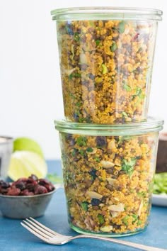 three glass containers filled with food sitting on top of a blue table next to a bowl of fruit