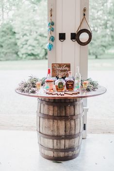 a wooden barrel table with liquor bottles on it and a sign hanging from the door