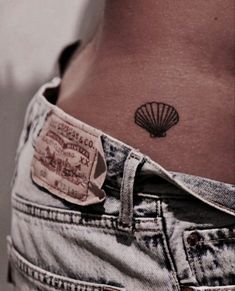 a woman's stomach with a small tattoo on her lower back, and a shell in the pocket