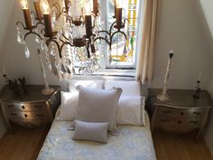 a bed with white pillows and chandelier hanging from it's side wall