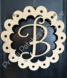 the letter b is made out of wood and sits on a black door with an ornate frame