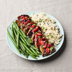 a white plate topped with green beans and chicken covered in strawberry sauce next to rice