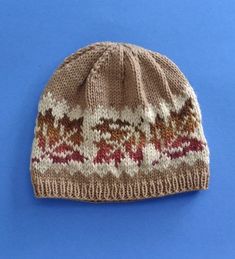 a knitted hat on a blue background with the pattern in red and beige colors