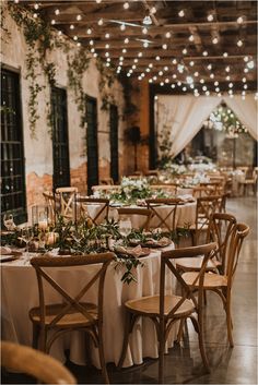 the tables are set with white linens and greenery for an elegant wedding reception