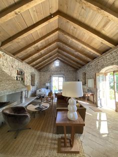 a living room filled with furniture and a fire place next to a stone wall covered in windows