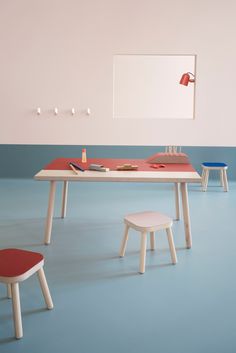 a table and two stools in a room with blue flooring on the walls