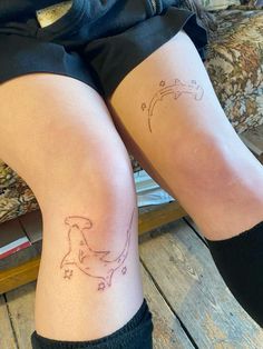 two people with tattoos on their legs sitting next to each other