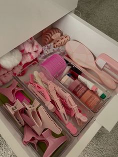 an open drawer filled with lots of pink items on top of a carpeted floor