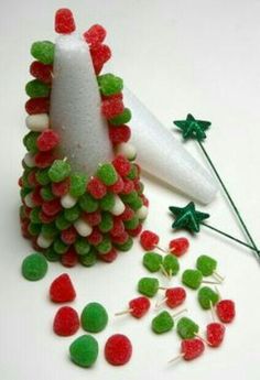 a pine cone made out of candy with green and red candies scattered around it