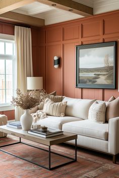 a living room filled with furniture and a painting hanging on the wall above it's windows