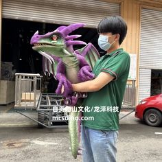 a man wearing a face mask and holding a purple dragon in front of a building