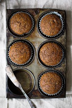 a muffin tin filled with lots of brown cupcakes on top of a table