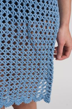 a close up of a person wearing a blue crocheted skirt