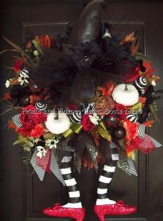 a wreath with black and white striped stockings, pumpkins and flowers on the front door