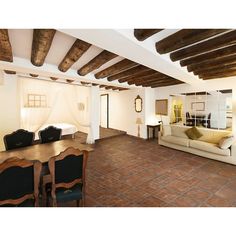 a living room filled with furniture next to a wooden table and chairs on top of a tiled floor