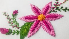 a pink flower with green leaves and flowers in the center on a white cloth background