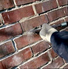 a person spraying water on a brick wall with a sprayer in front of them