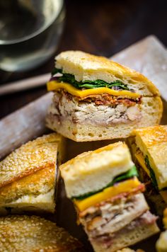 several sandwiches cut in half sitting on top of a cutting board next to some chips