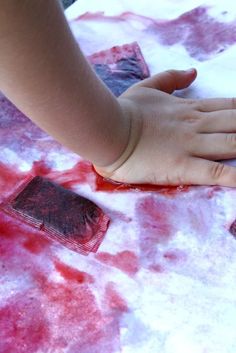 a child's hand on wax paper with red dye