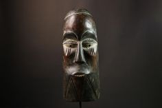 an african mask is displayed on a black surface with light coming from the top and behind it