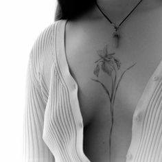 a black and white photo of a woman's chest with a flower tattoo on it