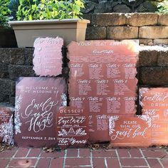 wedding seating signs on brick steps in front of a stone wall and potted planter