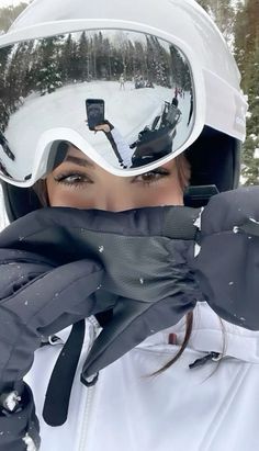 a woman wearing ski goggles and holding on to her jacket