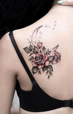 the back of a woman's shoulder with roses and a crescent tattoo on it