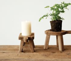 two small wooden stools with a potted plant on one and a candle on the other