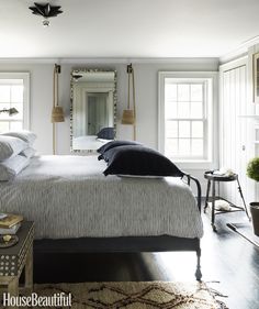 a bed sitting in a bedroom on top of a hard wood floor next to two windows