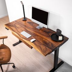 a wooden desk with a computer monitor and keyboard sitting on it's side, in front of a white wall