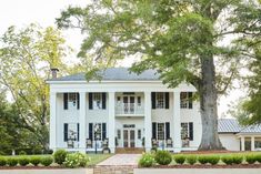 a large white house with black shutters and trees