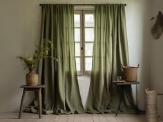 a room with green curtains and a table in front of the window that has a potted plant on it