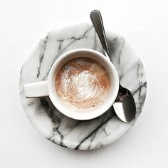 a cup of coffee sitting on top of a marble plate