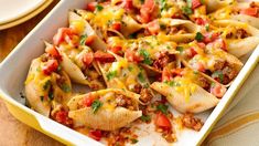 a casserole dish filled with tortilla shells covered in cheese and tomatoes