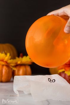 someone is holding an orange balloon in front of some pumpkins