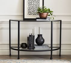 a table with books and vases on it in front of a framed art piece