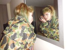 two women in camouflage jackets look at their reflection in the mirror