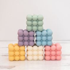 four small candles are stacked on top of each other in pastel colors and shapes